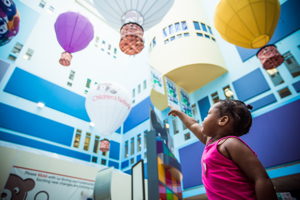 little girl pointing at atrium balloons