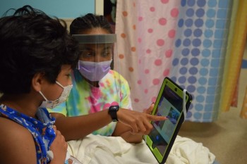 Child life specialist with young girl looking at tablet