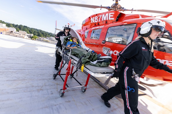Members of the emergency transport team wheel a patient on a stretcher past SkyBear helicopter