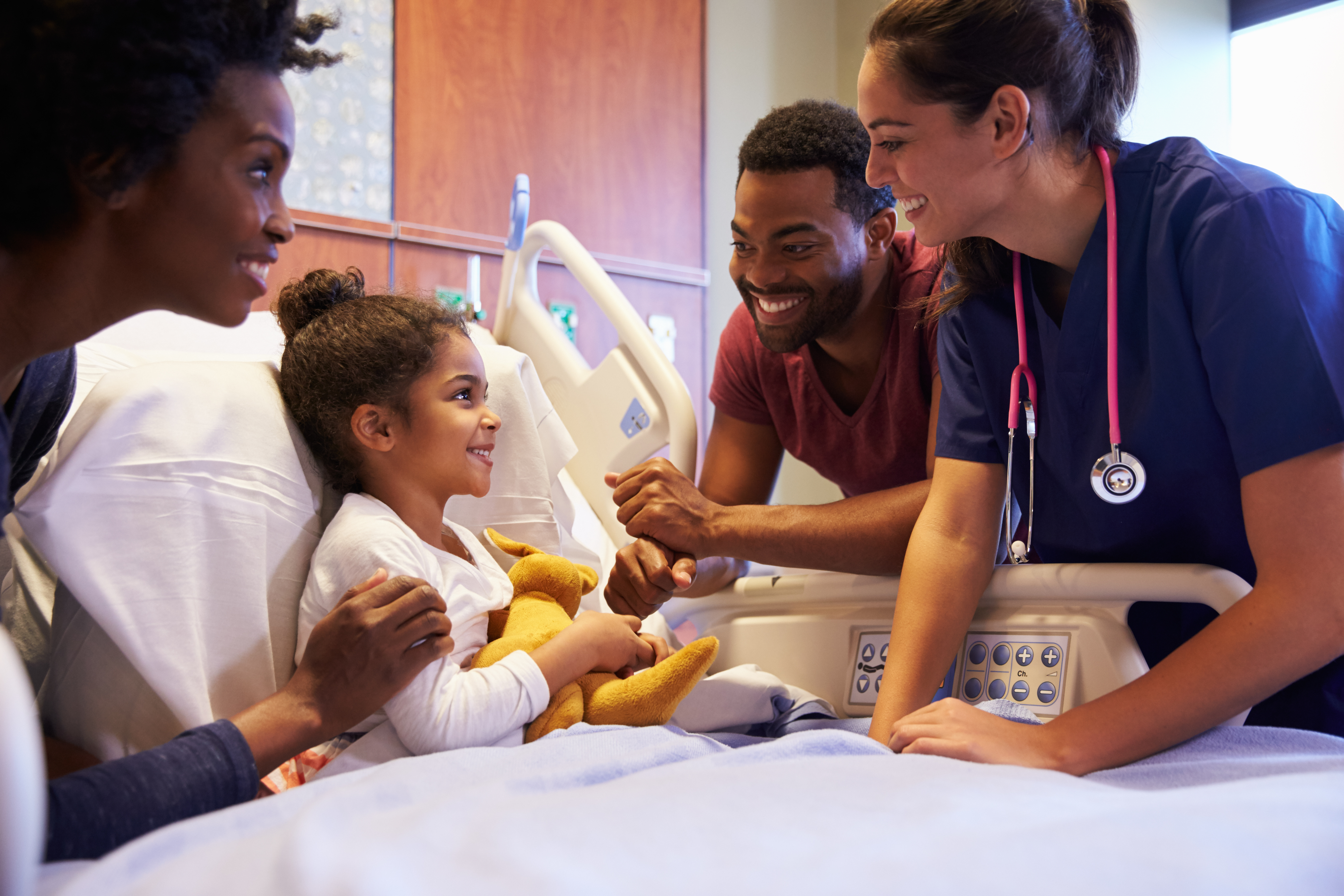 Doctors beside child in bed.