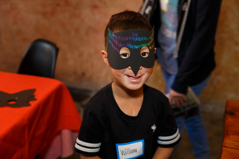 Little boy with a mask smiles at craniofacial party.